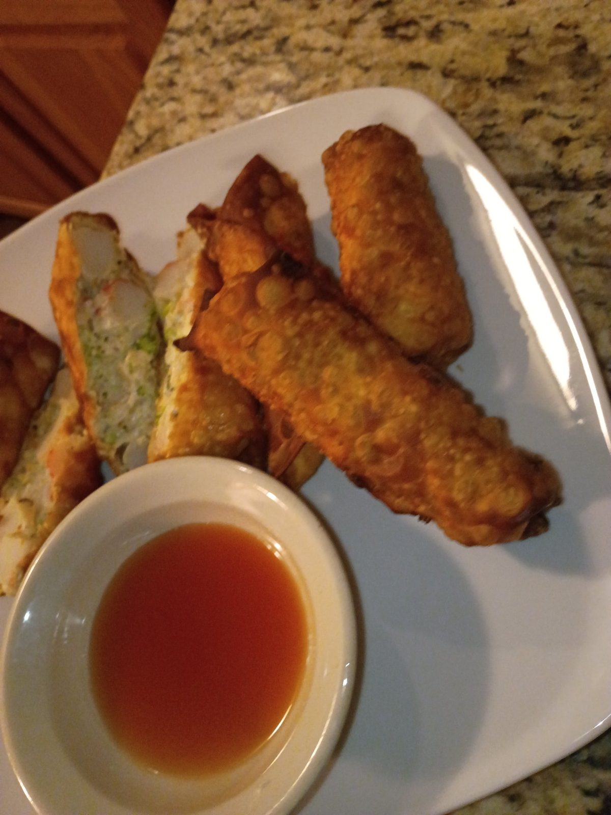 Crab Egg Rolls cut open with creamy crab and broccoli filling, Honey Thai sauce on the side